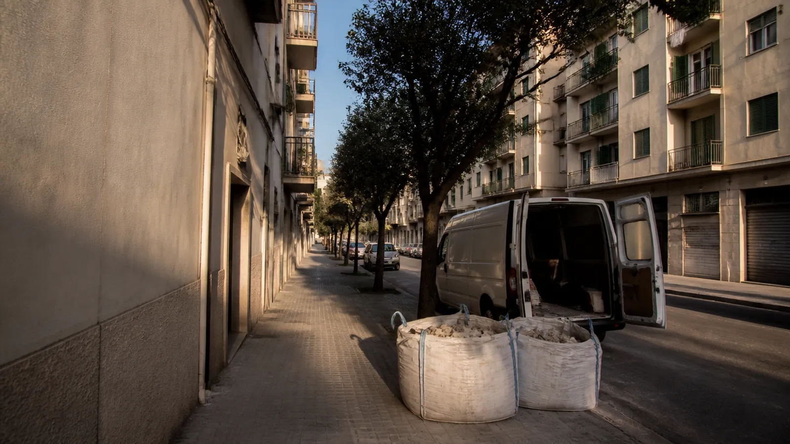 Sacas de escombro y furgoneta de carga junto a una finca de Valencia, listas para la retirada