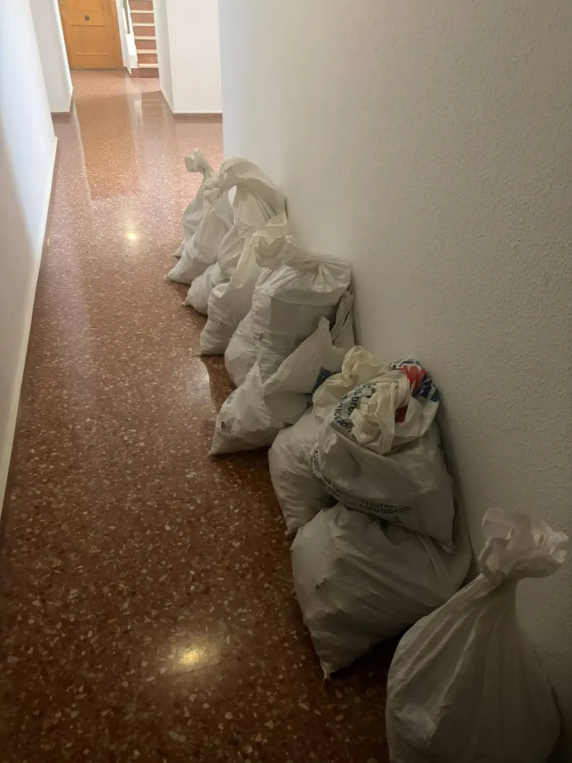 Sacos de escombro alineados en el pasillo de una finca
